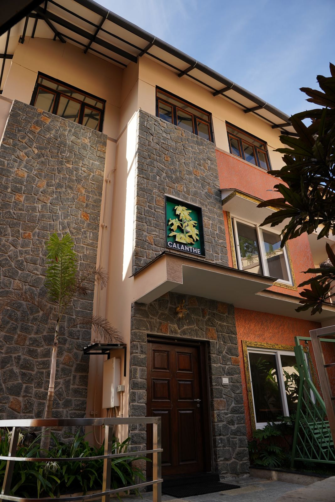 The Calanthe building's stone-and-render facade in daylight, with a small nameplate sign beside its entrance.