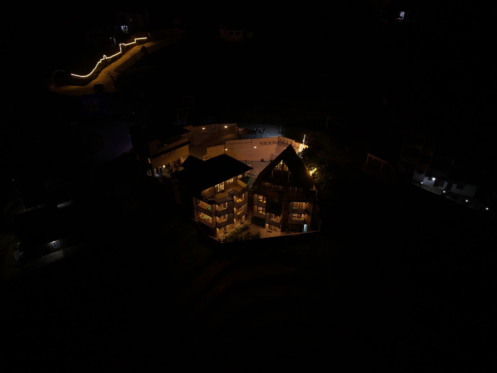 A drone view of the property at night, its buildings lit up amid the dark hillside.