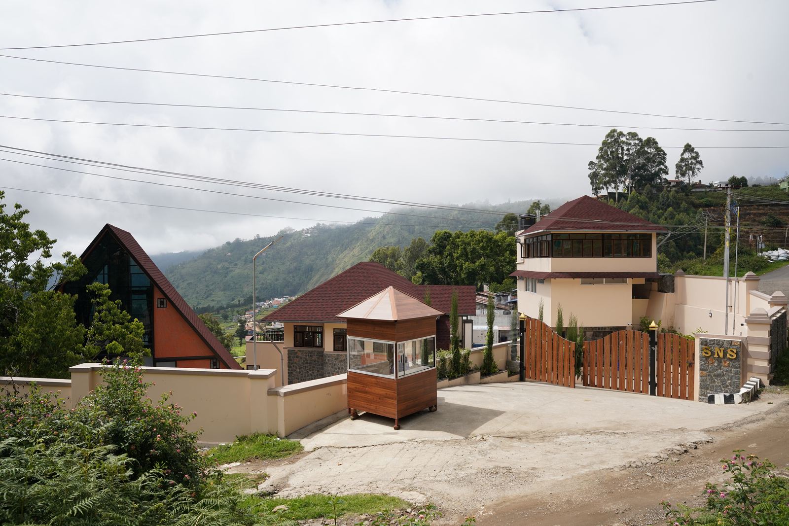 The whole property seen from the road, its buildings and guardhouse gathered on the hillside behind the entrance gate.