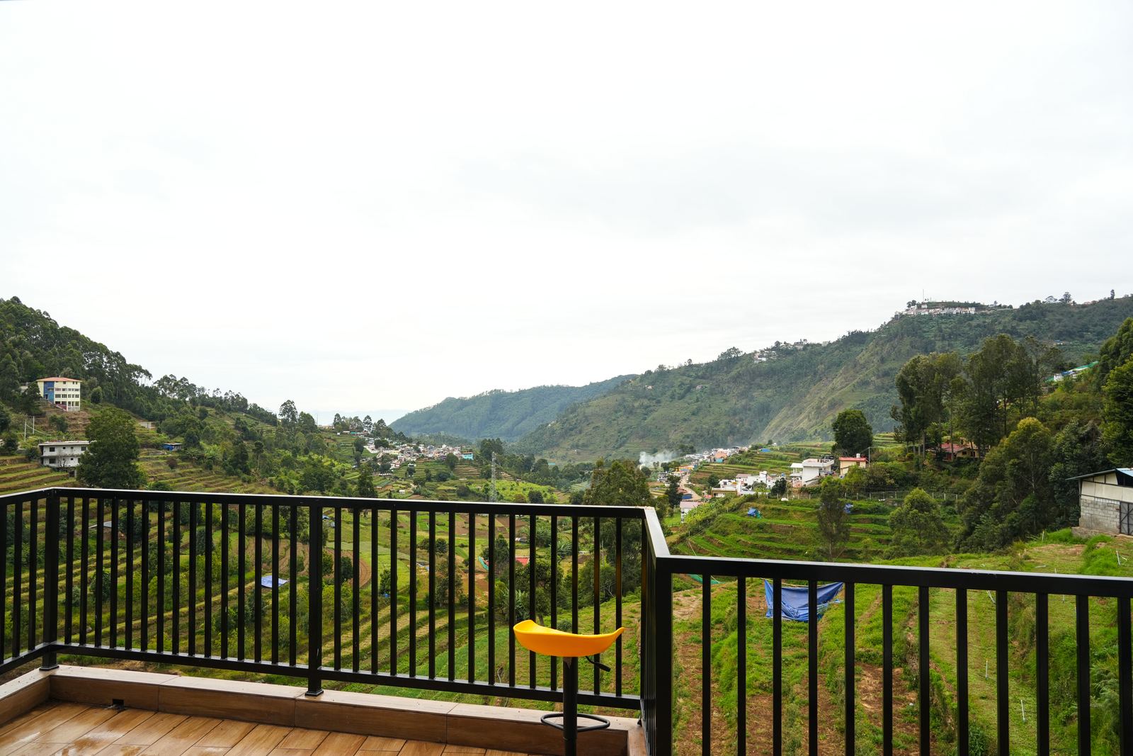 A wide balcony view over the terraced valley by day, hills receding toward the horizon.