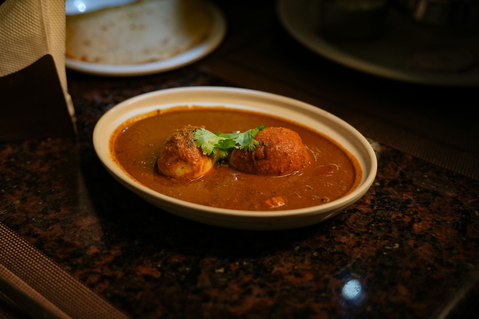 Sliced boiled eggs in a spiced tomato gravy, garnished with coriander