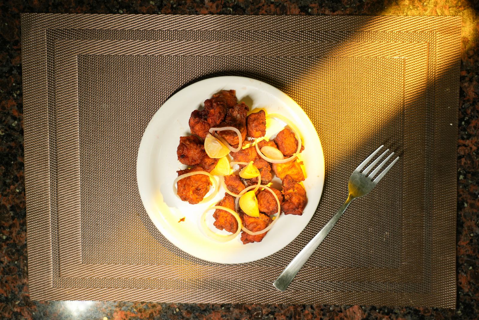 Crispy fried chicken pieces garnished with onion rings and lemon