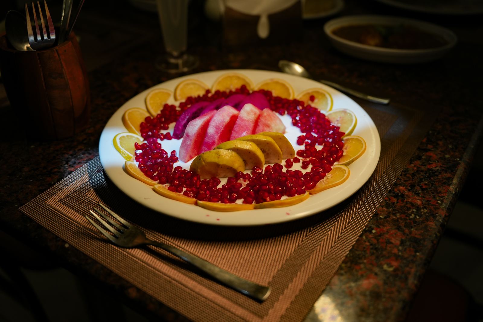 A fruit platter with orange slices, pomegranate seeds and melon