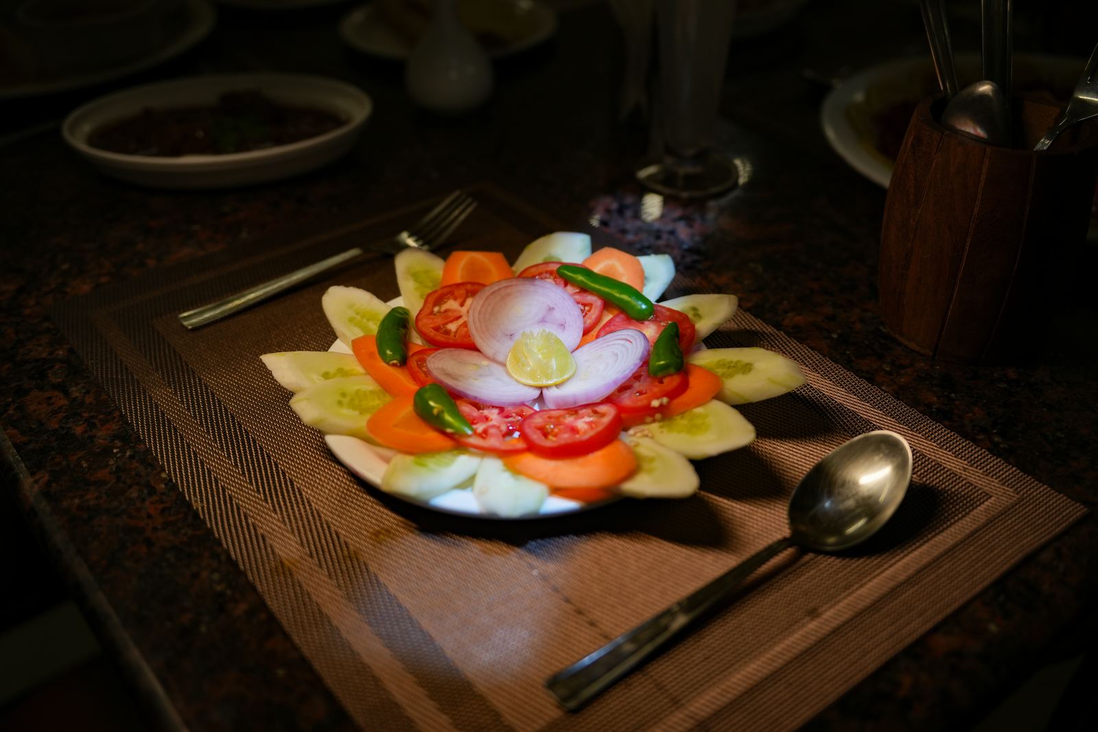 Sliced cucumber, tomato and onion arranged in a flower pattern on a plate